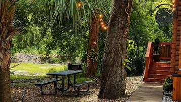 A park area with picnic tables, a concrete path, and trees.