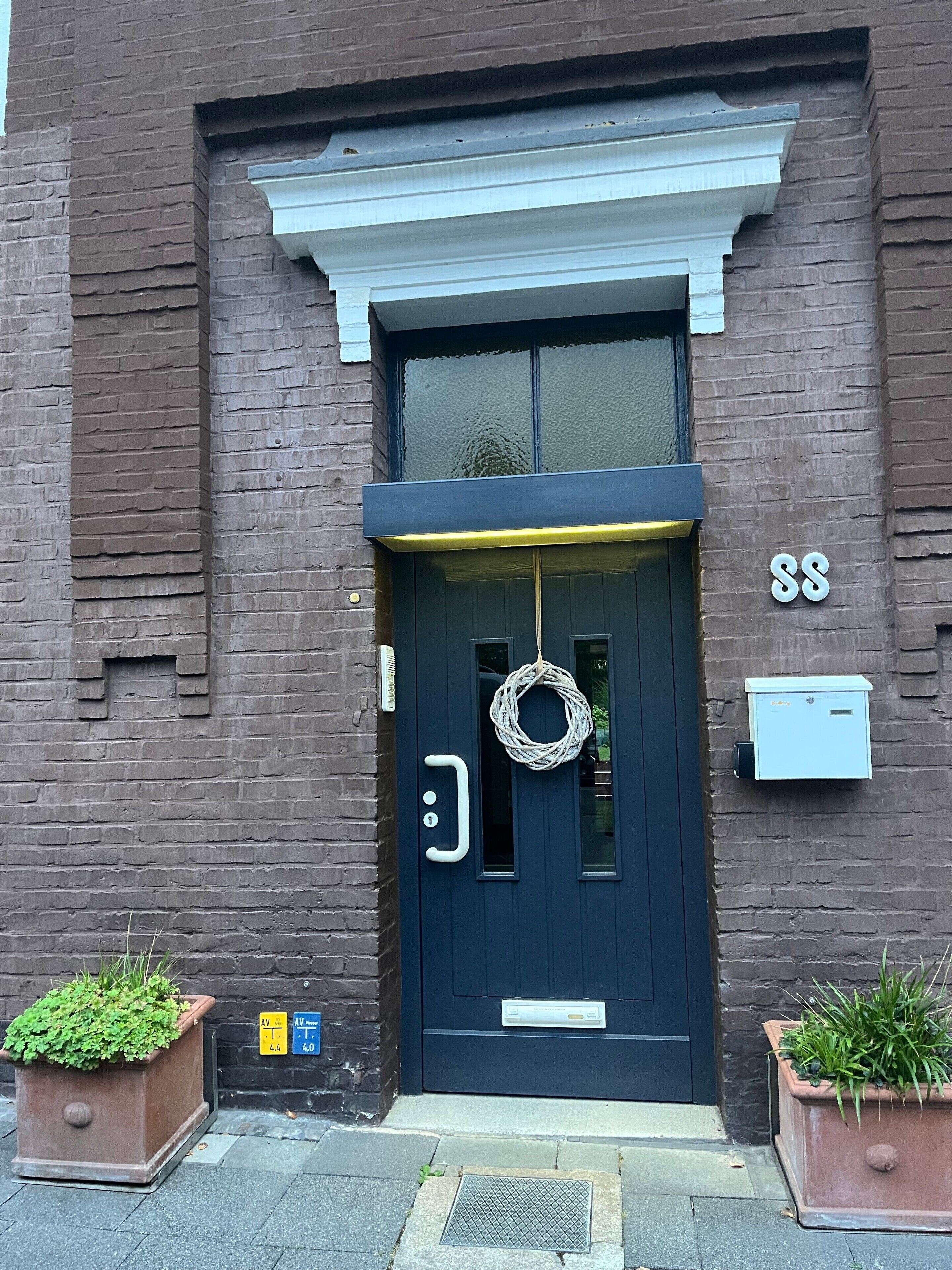 A dark blue door with a wreath hanging on it, a mailbox, and a number '88' on the wall.