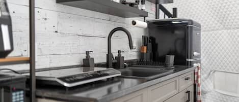 A modern kitchen with a black faucet, stainless steel appliances, and a white backsplash.