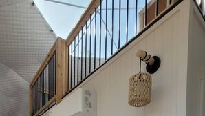 Una habitación con sofá, lámpara colgante y escalera de madera.