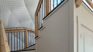 Una escalera de madera con barandillas negras que lleva a una puerta blanca.