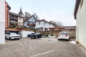 Zona residenziale con tre auto parcheggiate, un vialetto asfaltato e un mix di architettura moderna e tradizionale.