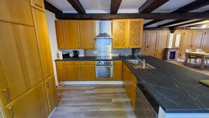 Een keuken met houten kastjes, een zwart aanrecht en een ingebouwde oven.