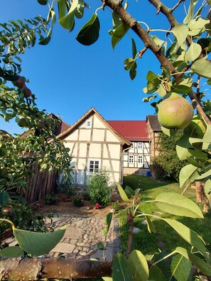 Ein traditionelles Fachwerkhäuschen mit rotem Dach, umgeben von einem Garten mit einem Kiesweg.