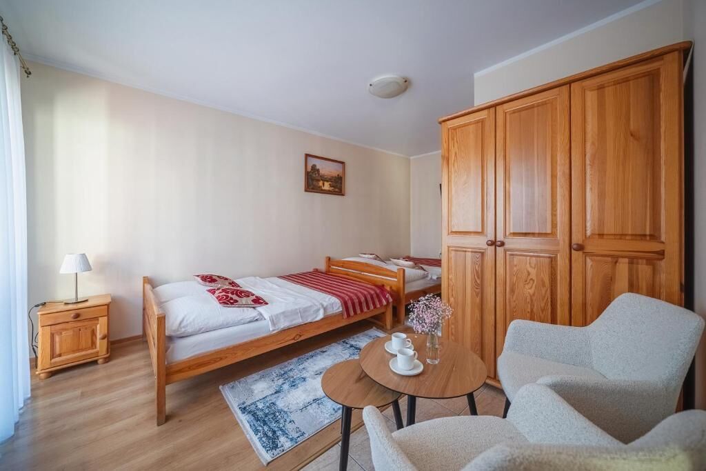 A room with a bed, a small table with cups, a chair, and a wardrobe.