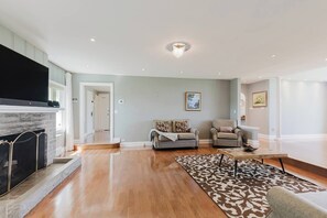 Ein geräumiges Wohnzimmer mit Kamin, zwei Sofas, einem Couchtisch und einem gemusterten Teppich.