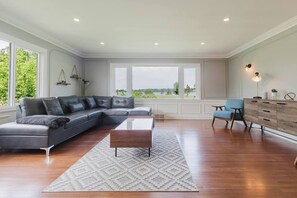 Ein geräumiges Wohnzimmer mit einem großen Ecksofa, einem Couchtisch, einem blauen Sessel und einer Holzkabine.