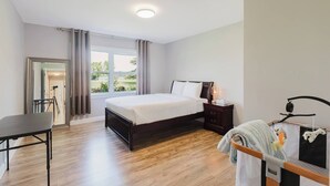 Quarto de hotel com cama, mesa de cabeceira, abajur e vista para o exterior.