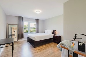 Ein Hotelzimmer mit Bett, Nachttisch, Lampe und Blick ins Freie.