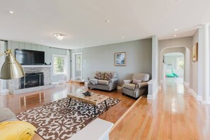 Ein geräumiges Wohnzimmer mit Kamin, zwei Sofas, einem Couchtisch und einem gemusterten Teppich.