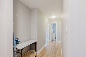 Ein Flur mit weißer Wand, einem kleinen Schreibtisch mit Korb und einer zur Toilette führenden Tür.