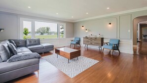 Uma sala de estar espaçosa com um sofá seccional, uma mesa de centro e duas cadeiras azuis.