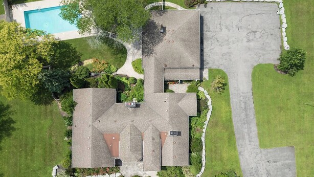 Um imóvel residencial com piscina, várias estruturas com telhado e gramado bem cuidado.