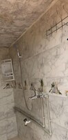 Un baño con paredes de mármol, ducha y barra para toallas.