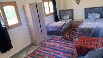 Quarto com duas camas, um guarda-roupa e uma janela.