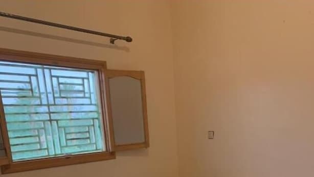 Une chambre à coucher avec un lit, une table de chevet, une fenêtre avec des stores et un miroir au mur.