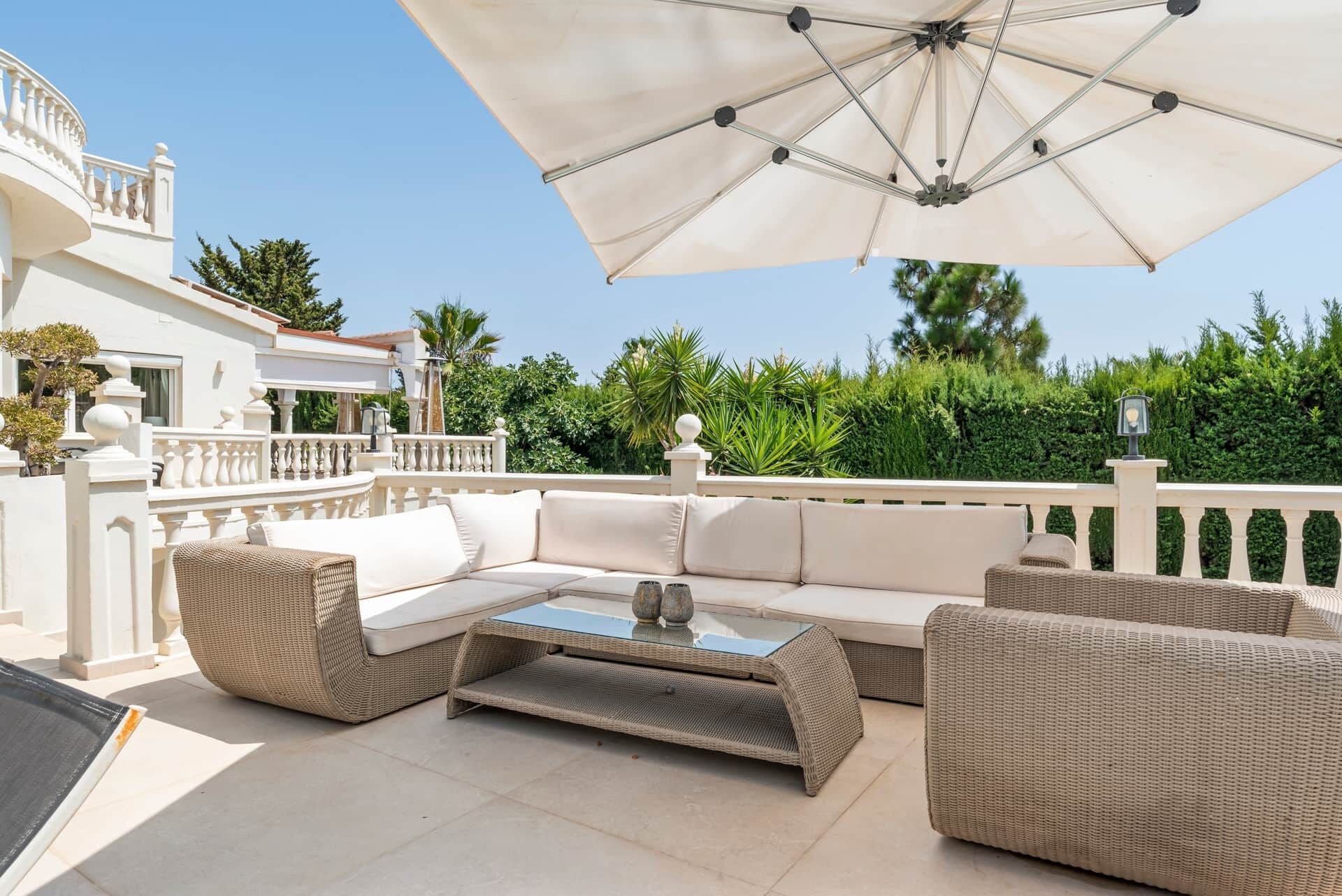 An outdoor seating area with a sofa, chairs, and a table, under a large umbrella.