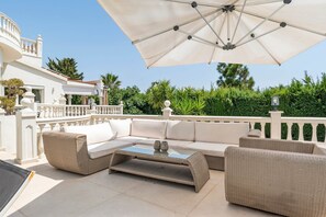 An outdoor seating area with a sofa, chairs, and a table, under a large umbrella. - Casa de los Suenos by Mabiente Properties (Mijas)