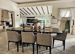 A dining area with a large table, four chairs, and a stone fireplace. - Casa de los Suenos by Mabiente Properties (Mijas)