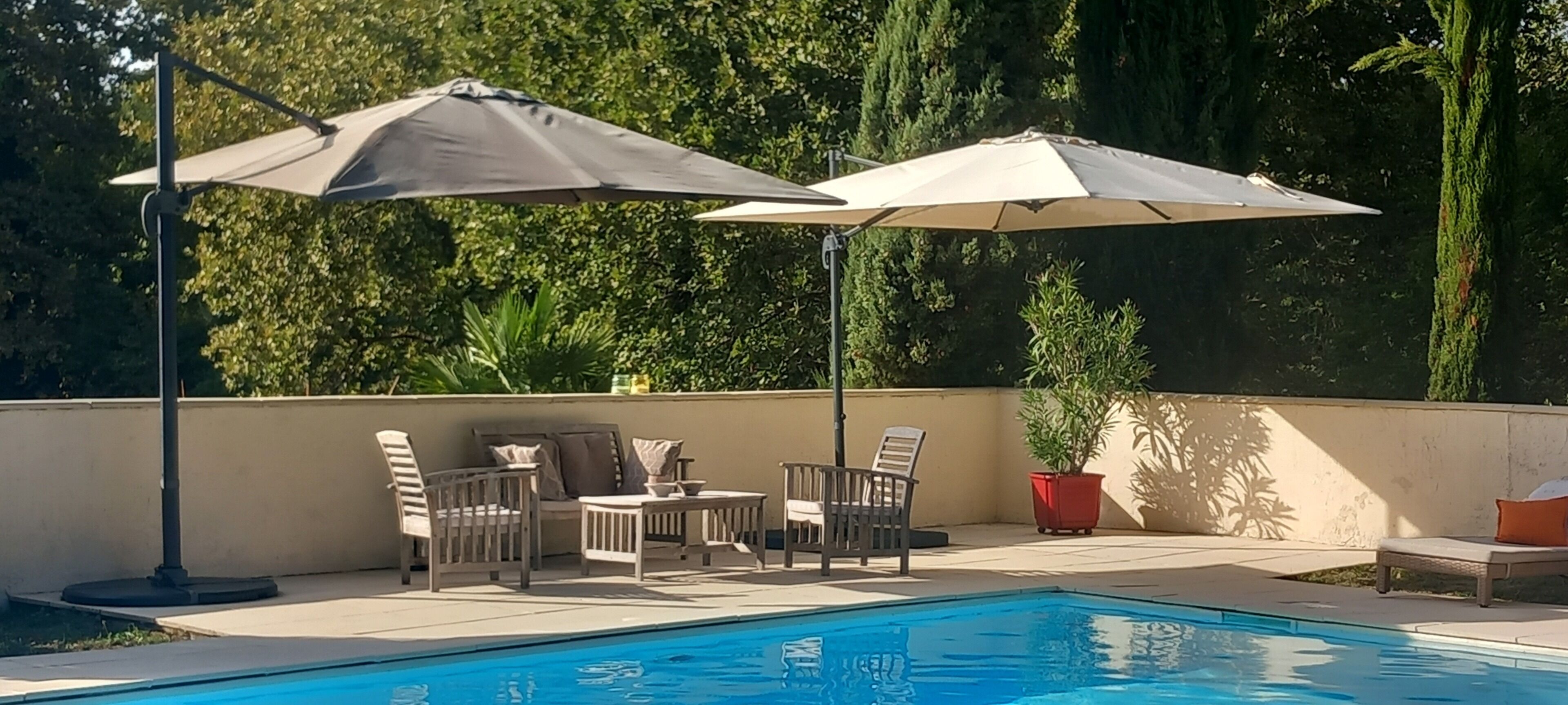 A poolside area with a pool, outdoor furniture, and umbrellas.