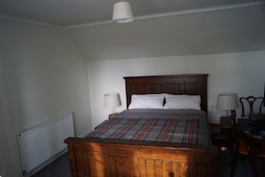 Un dormitorio con una cama de madera, dos lámparas de noche, un radiador y un escritorio con una silla.