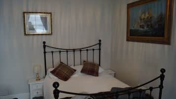 Une chambre à coucher avec un lit, une table de chevet, une lampe et deux tableaux encadrés accrochés au mur.