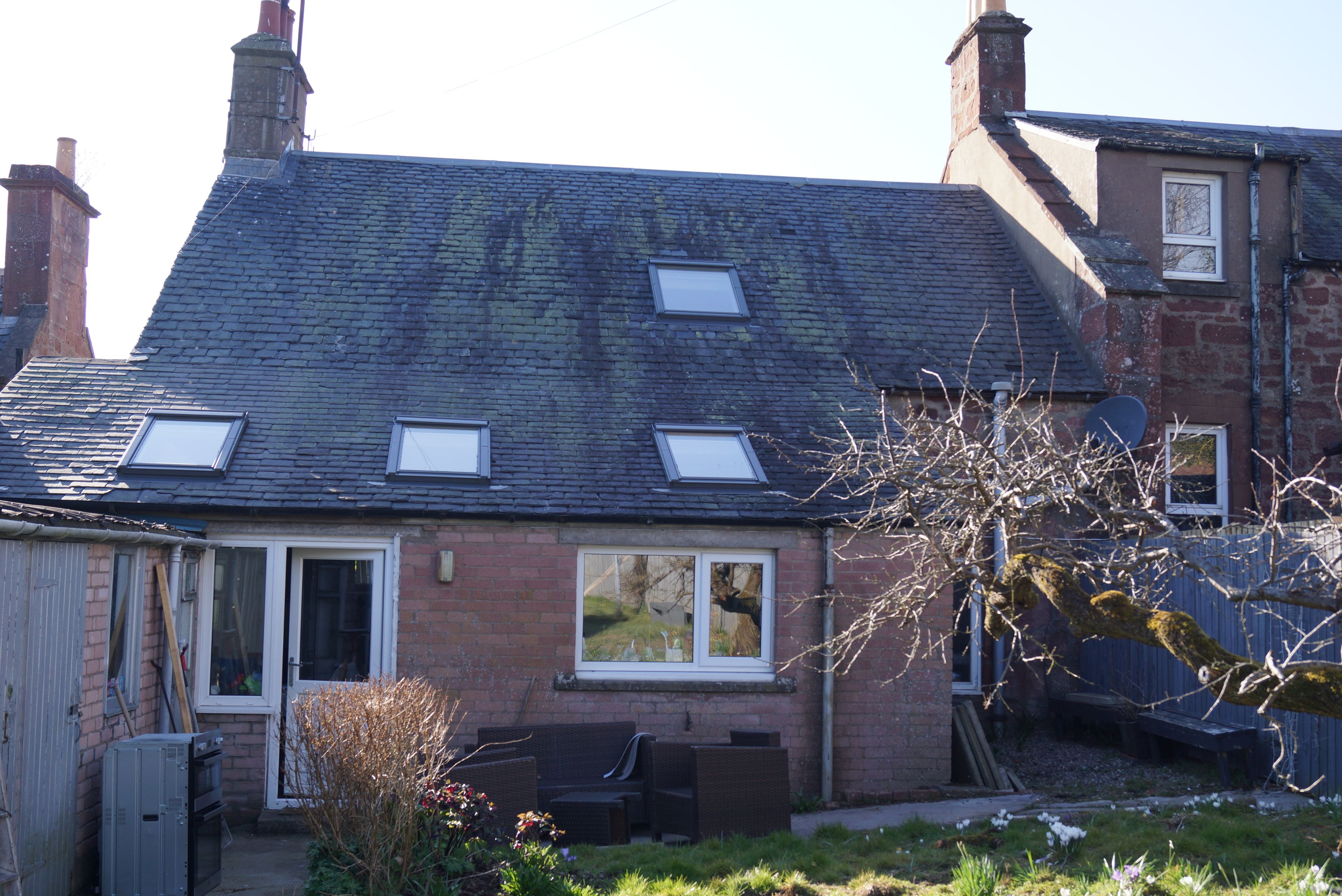 A two-story house with a sloped roof, dormer windows, and a brick exterior.