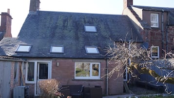 A two-story house with a sloped roof, dormer windows, and a brick exterior.