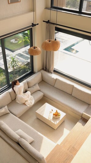 A modern living room with a large window, a beige sofa, a coffee table, and hanging rattan light fixtures. - Rua Sapanca (Sapanca)