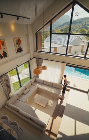 A modern interior with a large window, a sofa, and a view of a swimming pool. - Rua Sapanca (Sapanca)