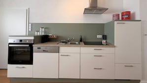 A compact kitchen with a built-in oven, dishwasher, and a stainless steel range hood.