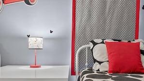 A bedroom with a white bedside table, a red lamp, a patterned wall, and a bed with a black and white patterned bedspread and a red pillow. - 8BR Pool/Spa, Themed Movie,Games and Kids Rooms. Disney area Waterpark Resort (Davenport)