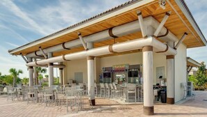 An outdoor cafe with a covered seating area and a storefront. - 8BR Pool/Spa, Themed Movie,Games and Kids Rooms. Disney area Waterpark Resort (Davenport)