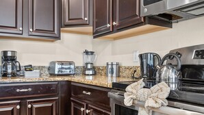 A modern kitchen with dark wood cabinets, stainless steel appliances, and granite countertops. - 8BR Pool/Spa, Themed Movie,Games and Kids Rooms. Disney area Waterpark Resort (Davenport)