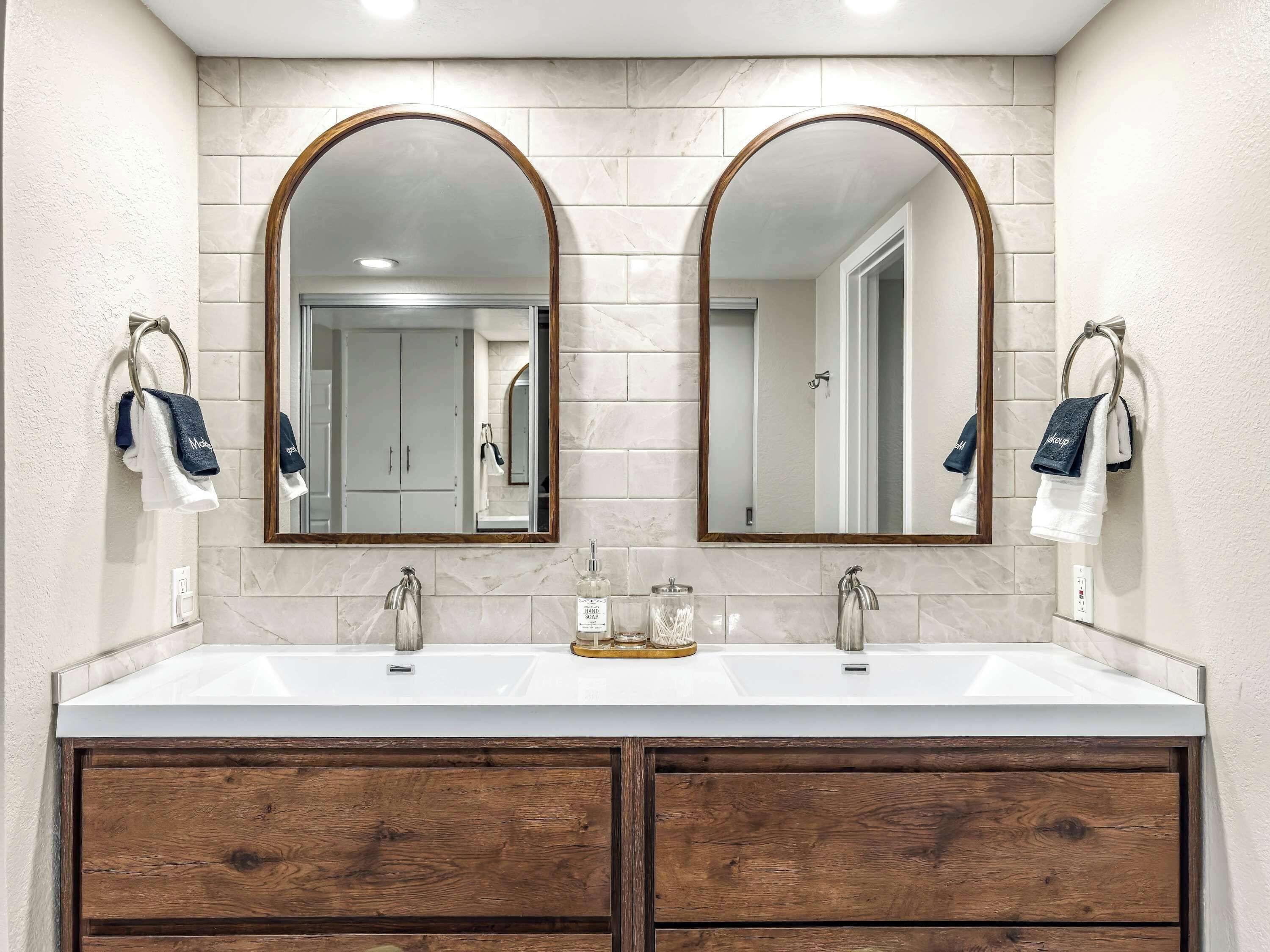 A bathroom with two sinks, a large mirror, and wooden cabinets.