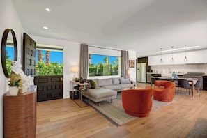 A modern living room with a sofa, armchairs, and a dining area with a kitchen in the background. - Casa Palmera-Mid Century Modern (Palm Springs)