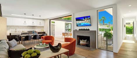 Una sala de estar moderna con chimenea, comedor y cocina.