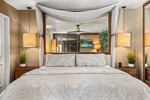 Une chambre à coucher avec un lit à baldaquin, deux lampes de chevet, un ventilateur de plafond et un grand miroir.