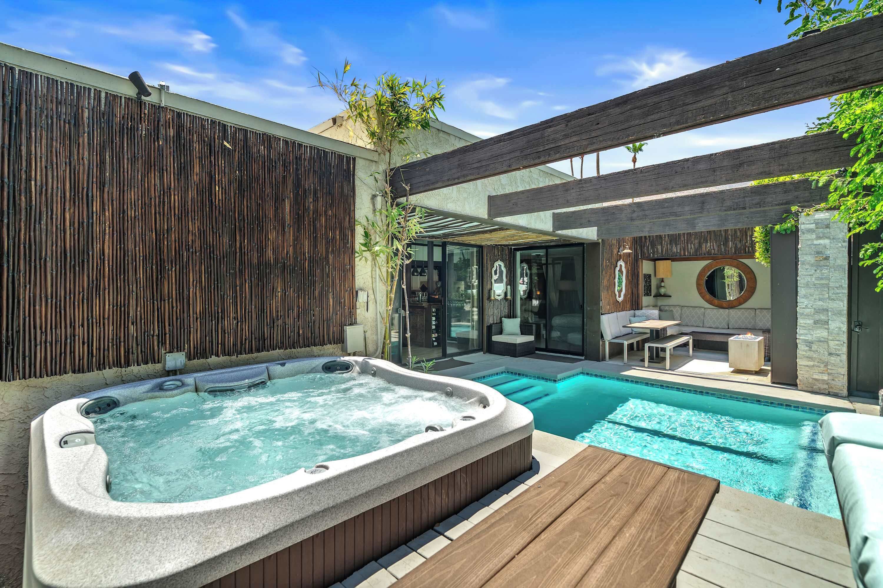 Ein moderner Poolbereich im Freien mit Whirlpool, Holzterrasse und Sitzgelegenheit.