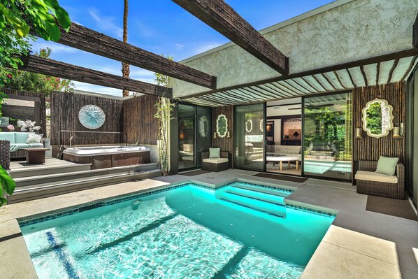 Un espace piscine extérieur moderne doté d’un jacuzzi, de coins salon et d’une terrasse fermée par des baies vitrées.
