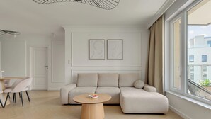 Ein modernes Wohnzimmer mit einer Couch, einem runden Couchtisch und einem Essbereich mit Stühlen.