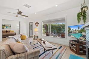 A modern living room with a sofa, coffee table, and a view of an outdoor pool area. - The Peacock House in Palm Springs (Palm Springs)