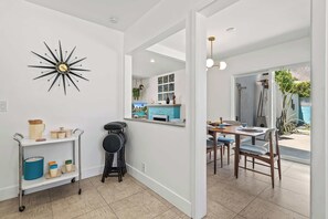 A modern kitchen with a dining area, a sunburst wall clock, and a view of a pool through the window. - The Peacock House in Palm Springs (Palm Springs)