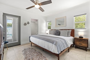 A bedroom with a bed, nightstands, a mirror, and a ceiling fan. - The Peacock House in Palm Springs (Palm Springs)