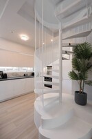 Una cocina moderna con una escalera espiral blanca, una planta en maceta y un salpicadero de mármol.