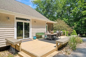 A house with a deck, a sliding glass door, and a patio with outdoor furniture.
