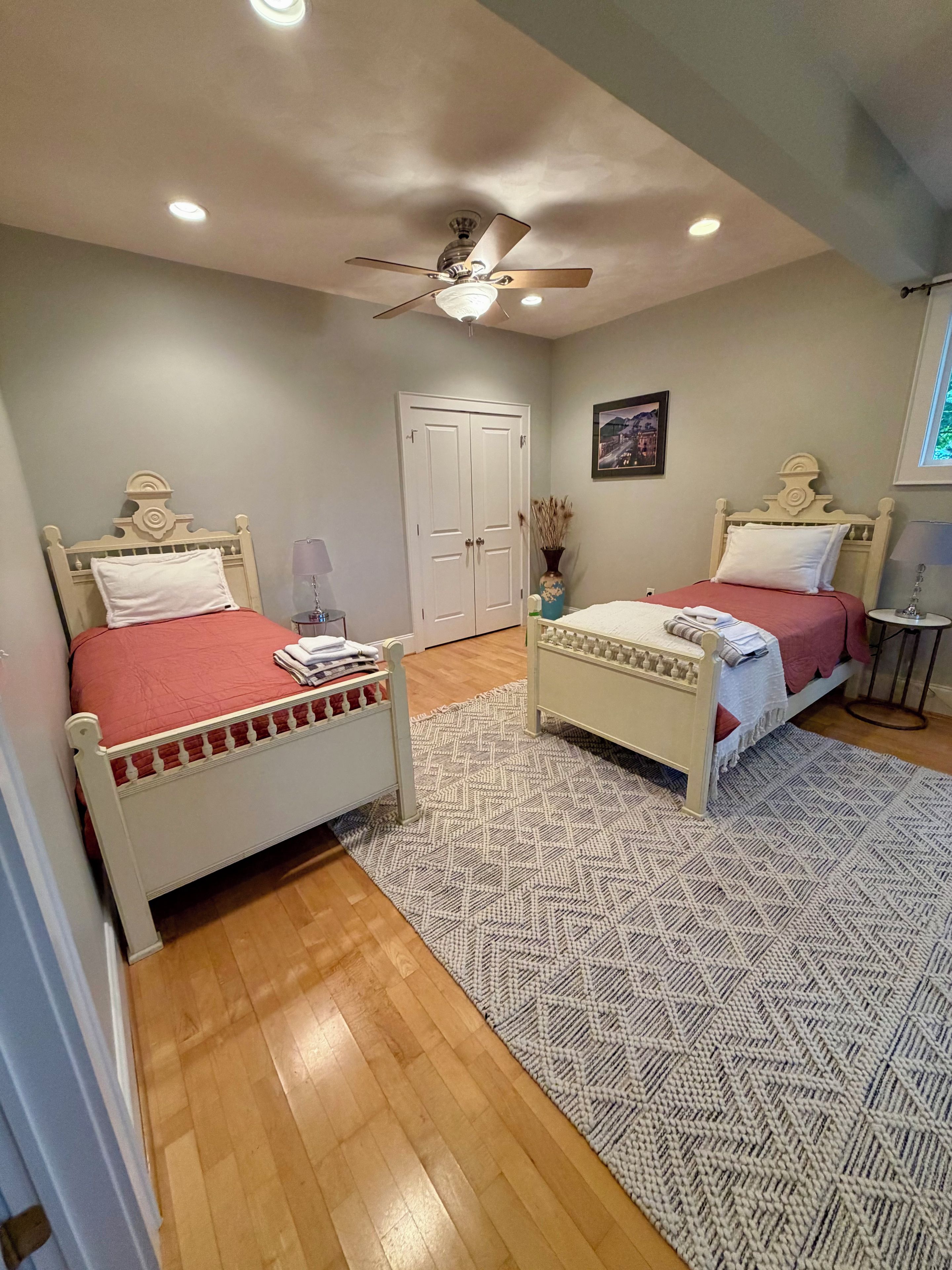 Une chambre avec deux lits, un ventilateur de plafond et un tapis à motifs.