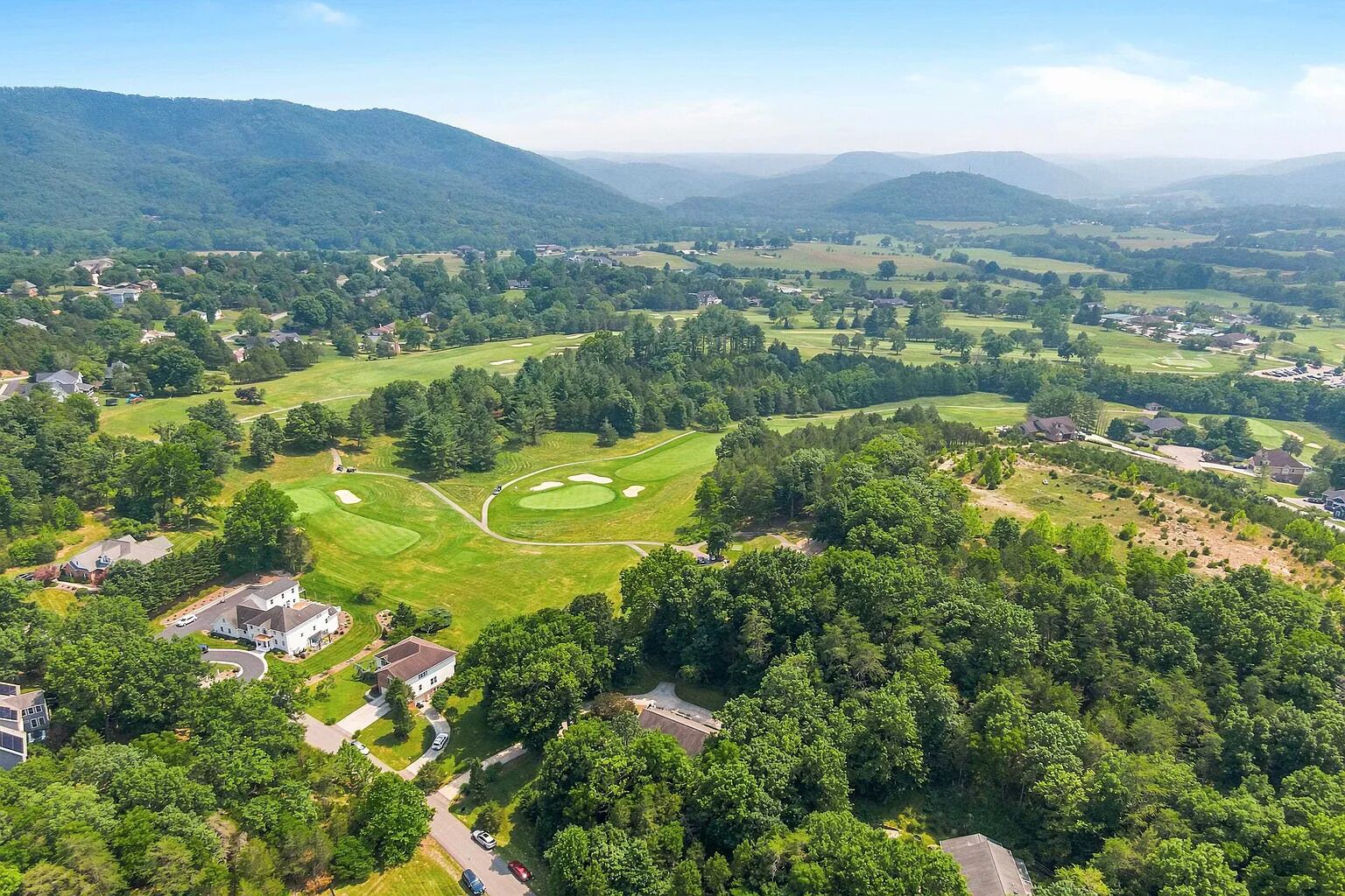Un parcours de golf comportant plusieurs trous, entouré de zones résidentielles et de forêts denses.