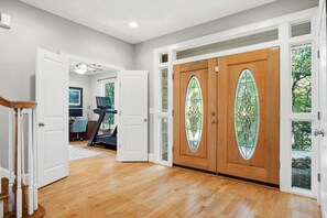 A spacious hallway with wooden flooring, a treadmill, and a door leading to a room with a large window.