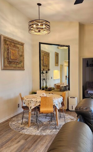 A dining area with a round table, chairs, a mirror, and a ceiling light fixture. - Furnished cozy 2-bedroom/2-bathroom condo 
in the resort-style gated community. (Boynton Beach)